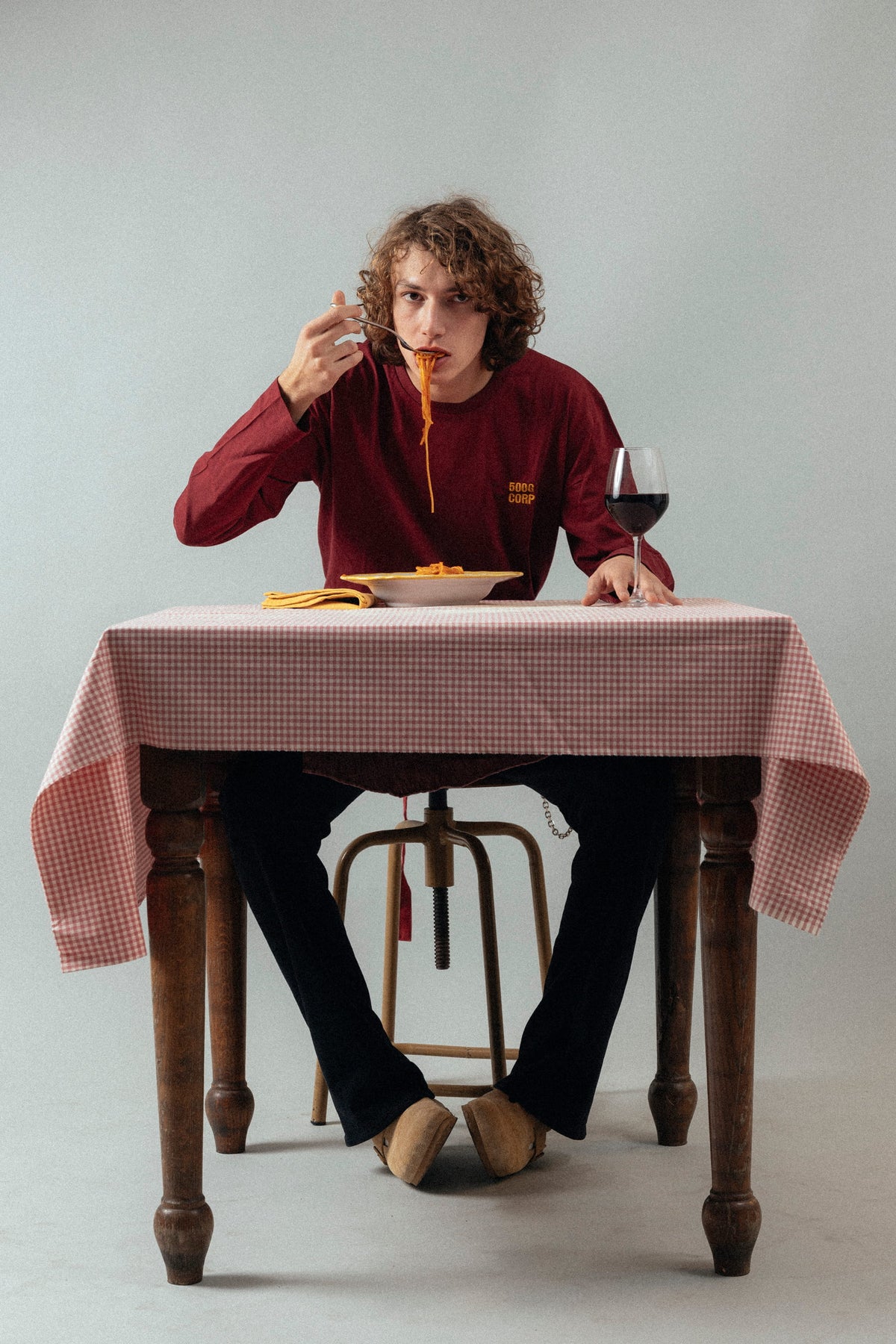 Une personne en sweat 500GCORP mange des spaghetti à table.